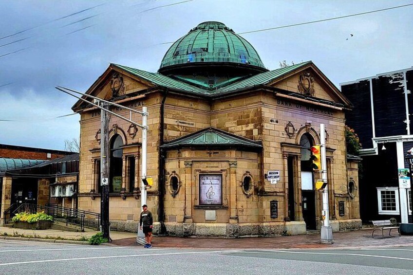 A historic building with a green dome, a clock, and a sign reading 'Bank of Montreal.' 1
