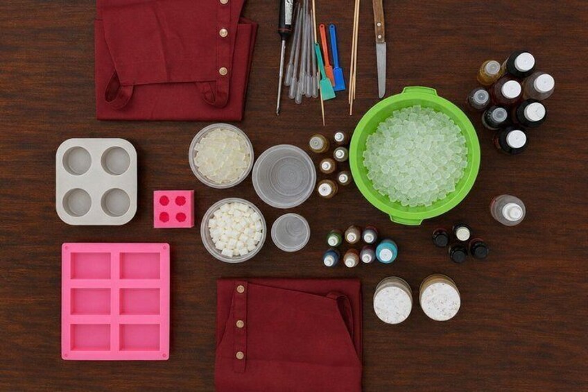 A wooden surface with various kitchen items like a pink silicone mold, a green bowl, and several small containers. 1