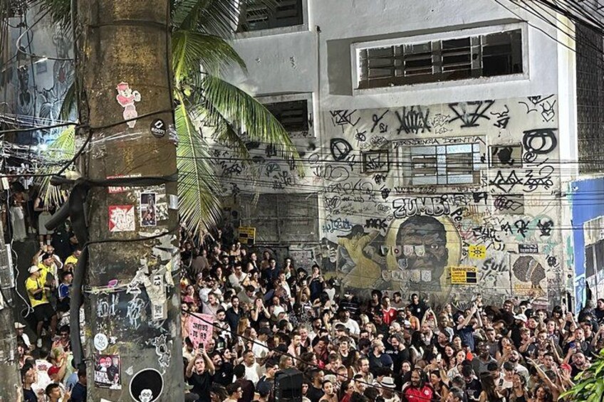 A crowded urban scene with graffiti-covered walls and a palm tree. 2