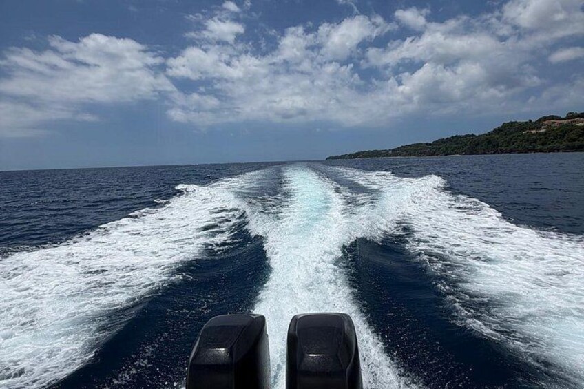 A boat's wake on a calm sea with a clear sky and a coastline in the distance. 4