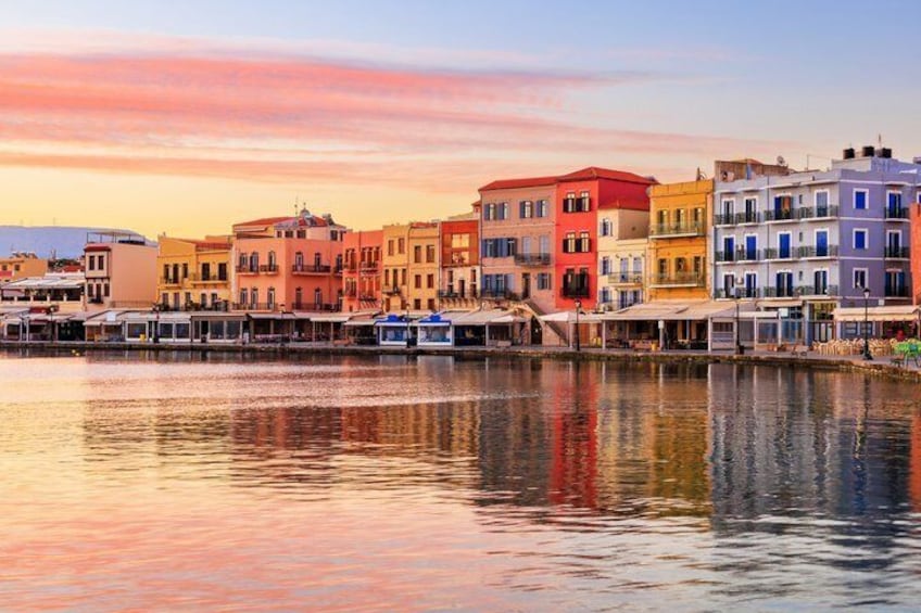 A waterfront with colorful buildings reflecting on calm water during sunset. 3