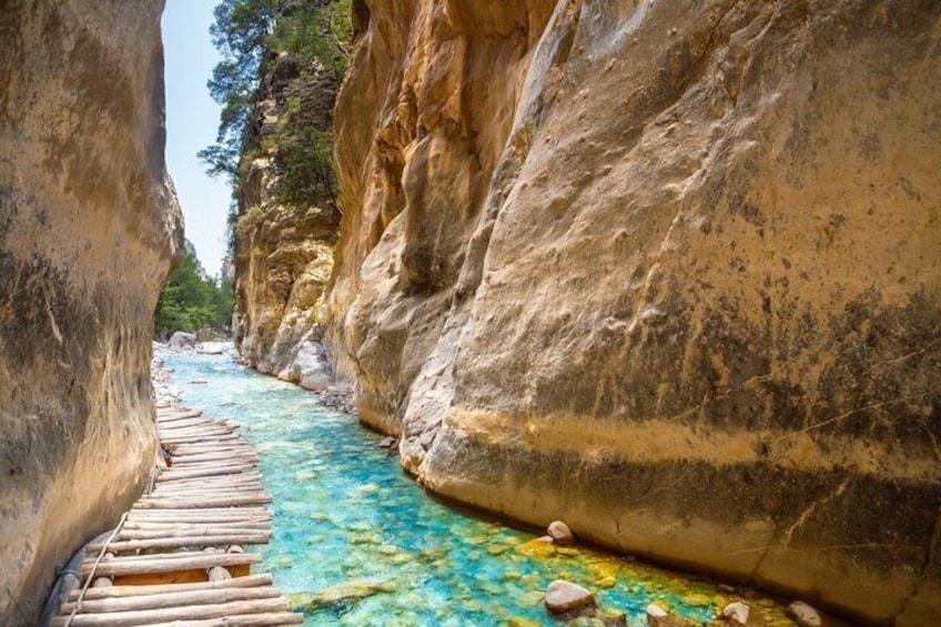 A narrow canyon with a wooden walkway and a turquoise river. 1