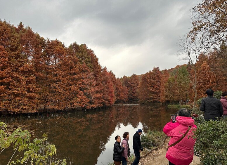 A group of people walking along a riverbank with autumn-colored trees reflecting in the water. 2