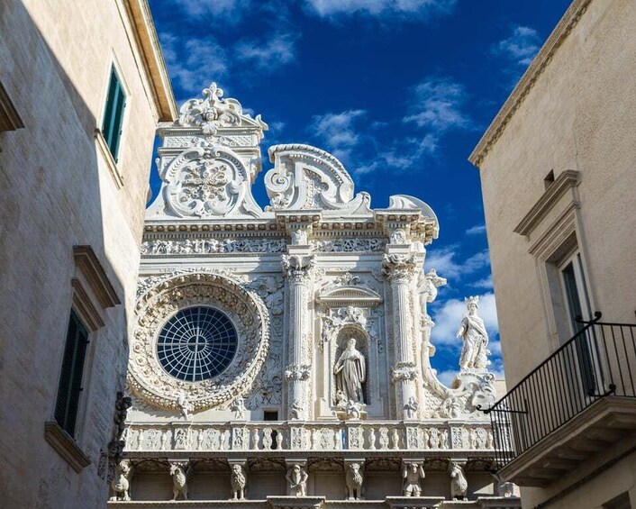 A detailed facade of a historic building with ornate sculptures and a large circular window. 5