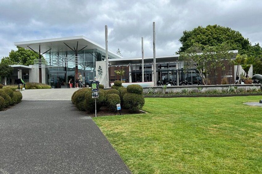 A modern building with a glass facade, surrounded by a well-maintained lawn and a paved walkway leading to the entrance. 5