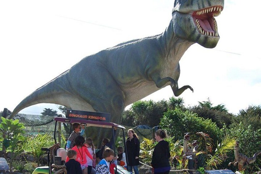 A large dinosaur statue, a sign reading 'DINOSAUR KINGDOM,' and people around it. 3