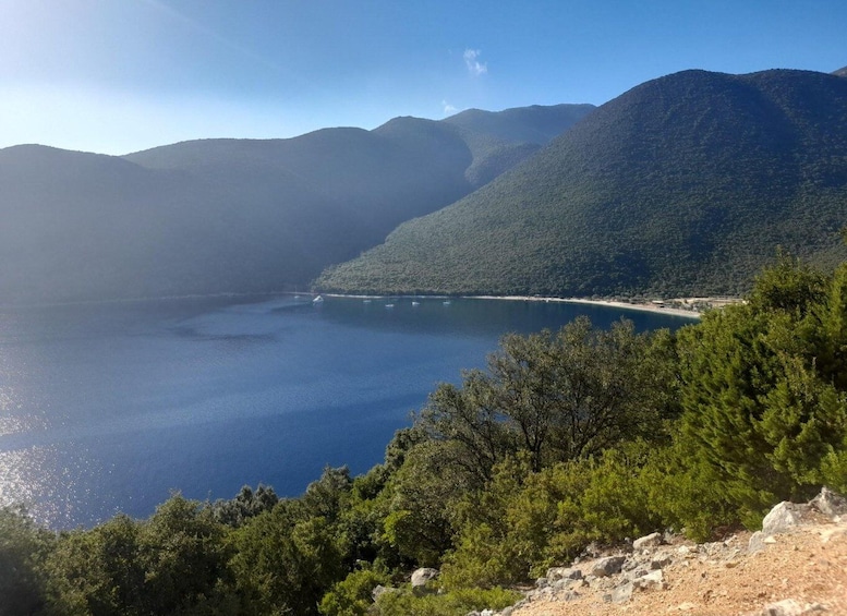 A coastal landscape with a clear view of a bay, surrounded by mountains and dense greenery. 4