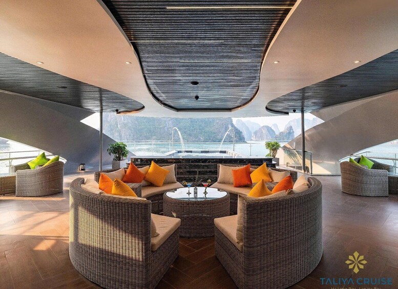 A modern yacht interior with wicker furniture, a central coffee table, and a view of the sea and mountains. 2