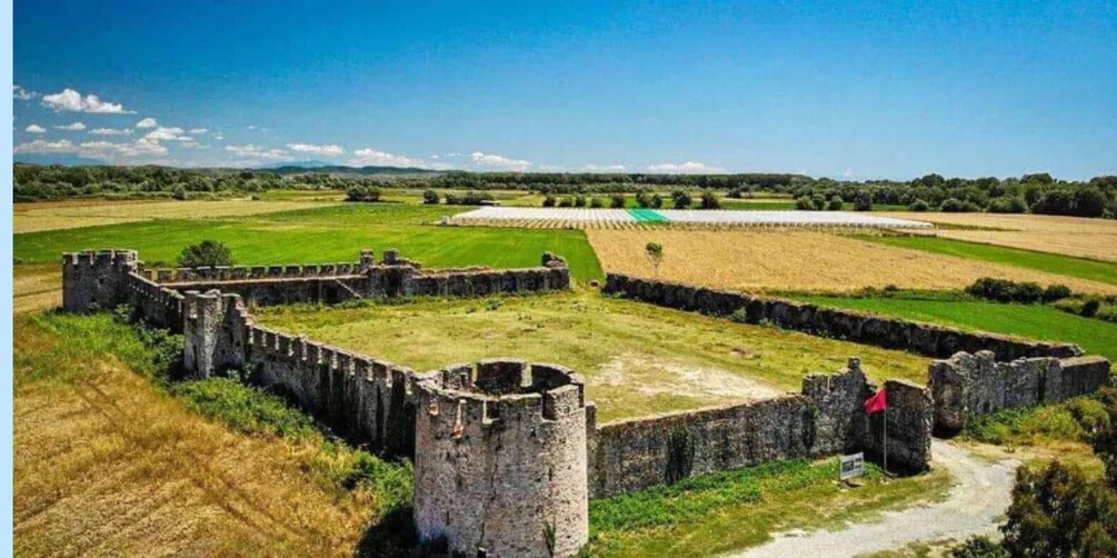 A medieval castle ruin with surrounding fields and a clear sky. 2