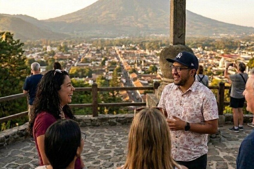 A group of people on a stone platform overlooking a town with a mountain in the background. 1