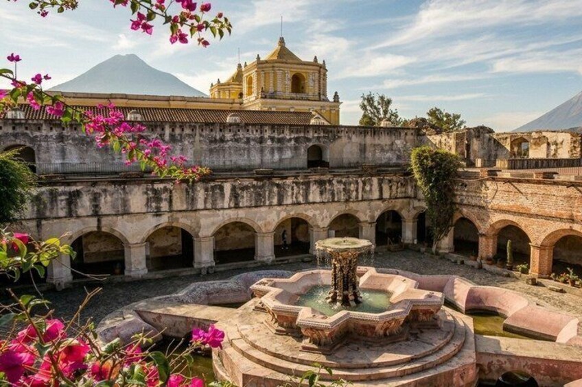 An ancient courtyard with a fountain, arches, and a prominent building with a dome. 4