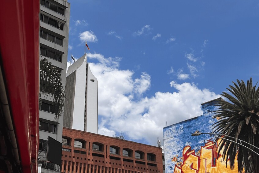 A tall building with a flag, a mural, and a palm tree. 3