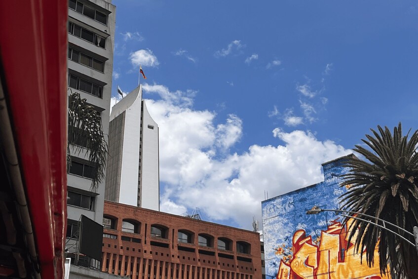 A cityscape with a tall white building, a red structure, and a mural on a building. 4