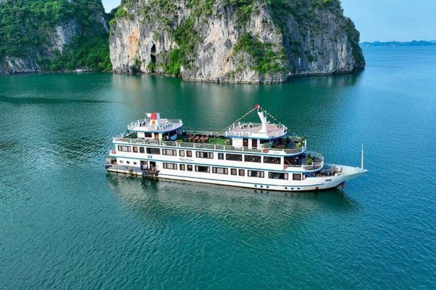 Un barco crucero blanco con varios niveles y una bandera, navegando por un río tranquilo con un acantilado rocoso al fondo. 1