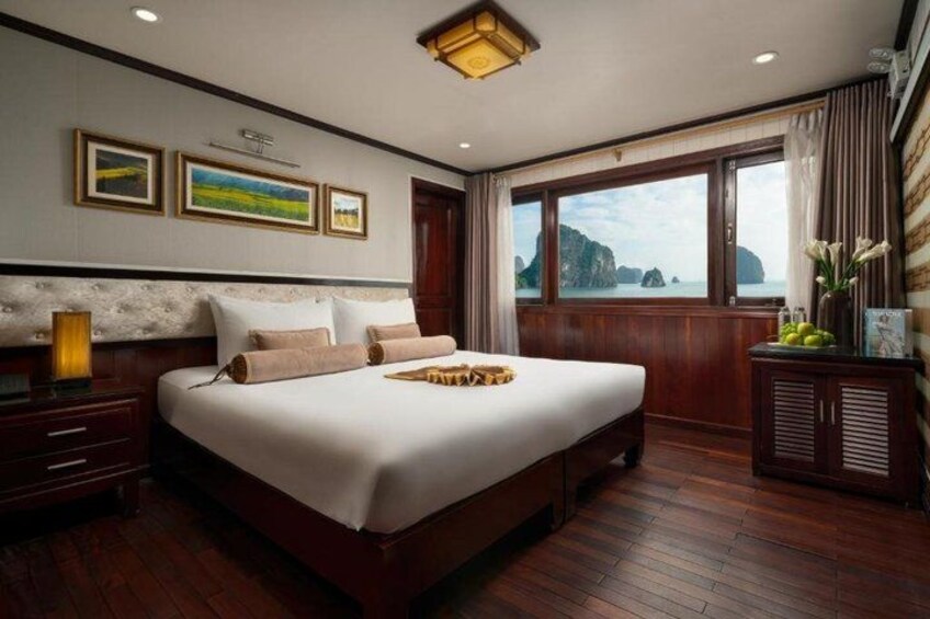 Una cama grande con cabecera de madera, una mesita de noche y un aparador con un florero. 2
