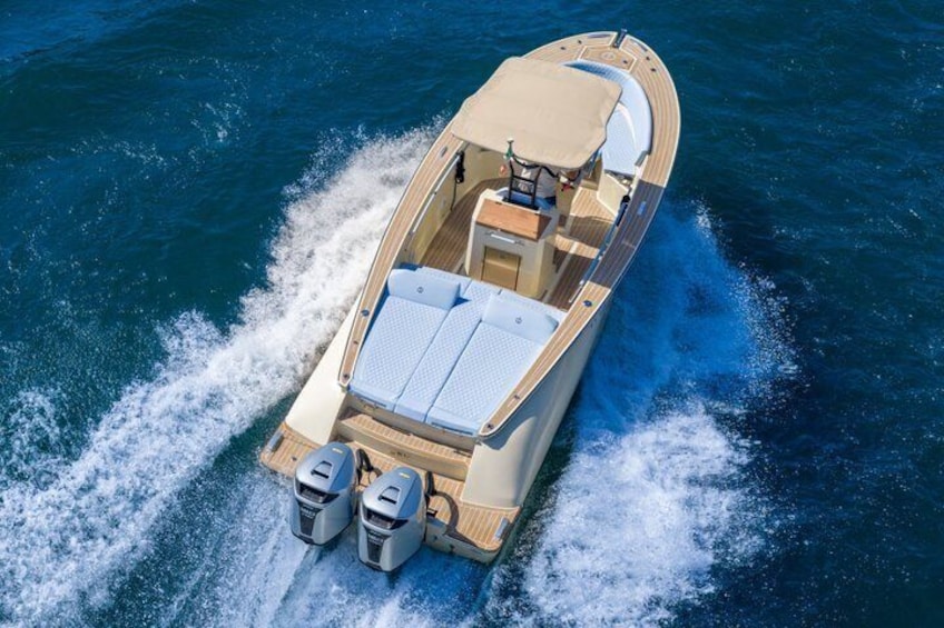 A speedboat with a wooden deck, two outboard motors, and a canopy. 5