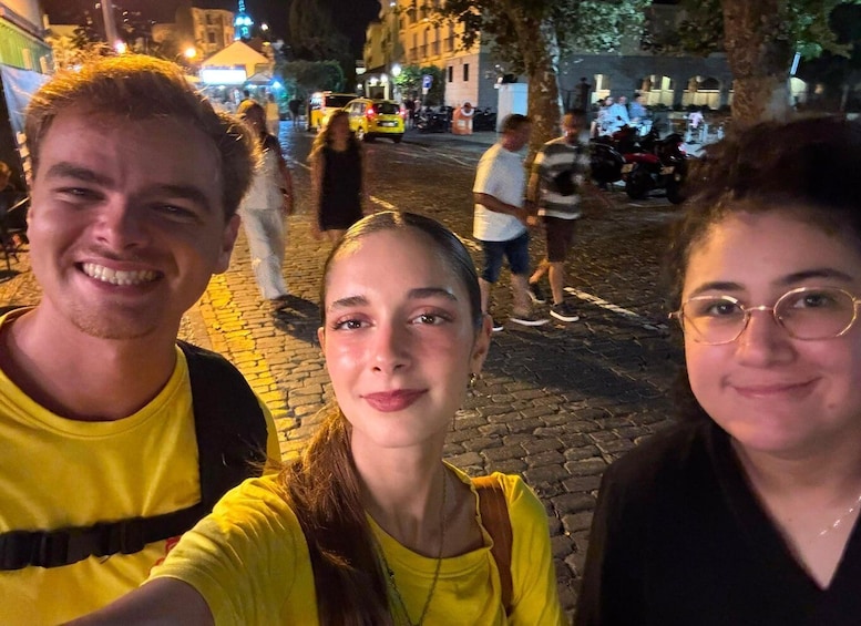 A group of people taking a selfie on a cobblestone street at night. 2