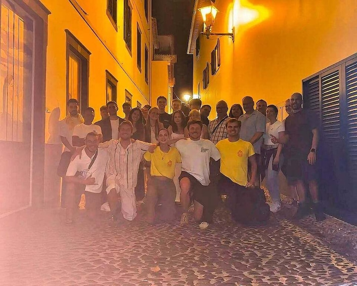 A group of people posing on a cobblestone street at night. 4