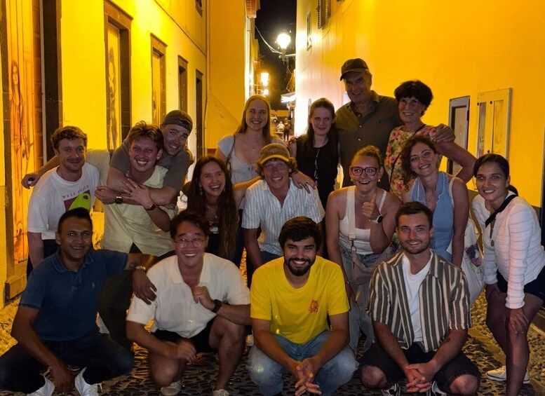 A group of people posing in a narrow street at night. 3
