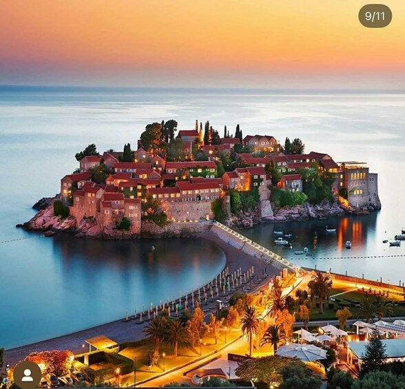 A coastal town at dusk with illuminated buildings, a calm sea, and a promenade. 2