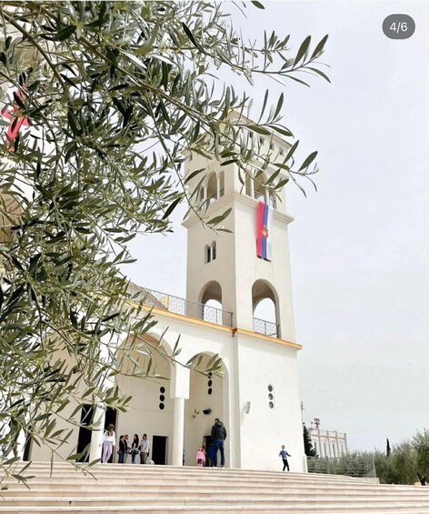 A white church with a bell tower and a flag. 3