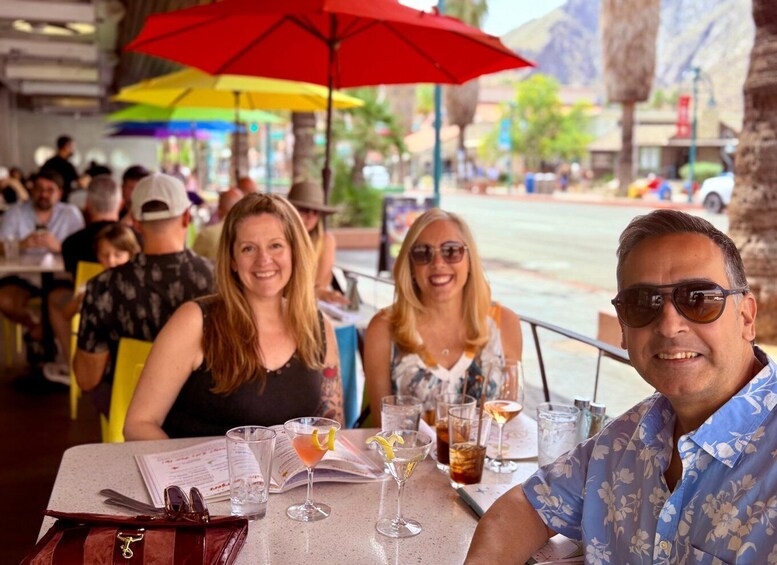 A group of people dining at an outdoor restaurant with colorful umbrellas. 5
