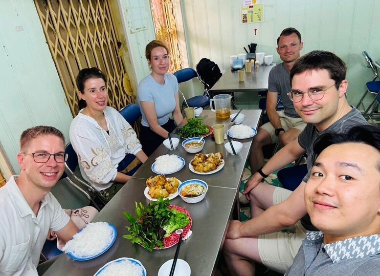 A group of people seated around a table with food and drinks. 5