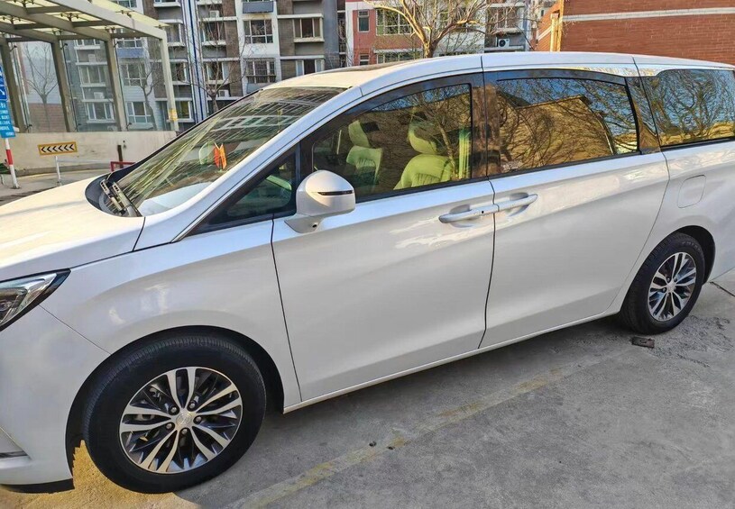 Valkoinen auto on pysäköity betonipinnalle, taustalla näkyy rakennus ja puita. 3