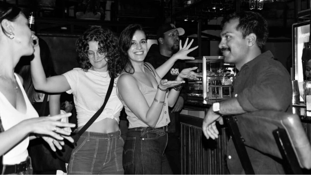 A group of people at a bar with a bartender. 5