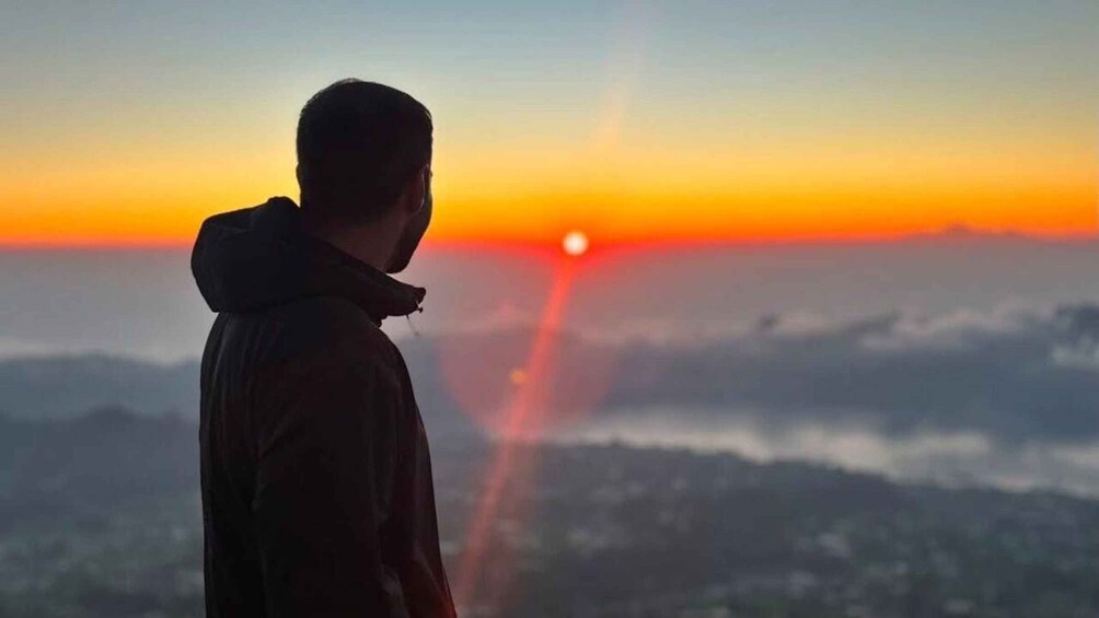 A person standing with a sunset in the background. 1