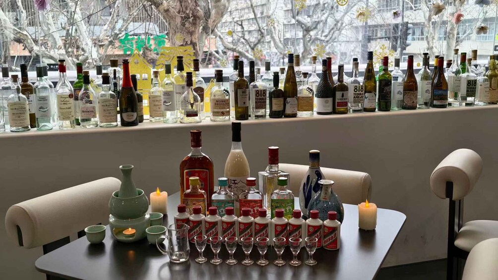 A bar with a variety of liquor bottles and glasses on a table, with a candle and a green teapot. 2