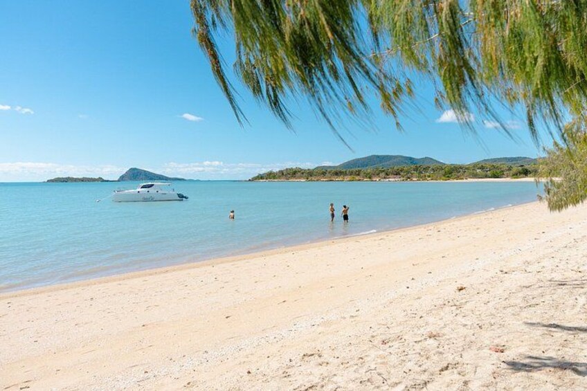A beach with a boat, people, and a mountain in the background. 4