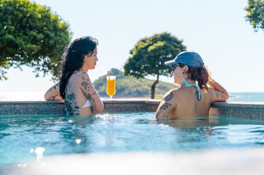 Two people in a swimming pool with trees and a clear sky in the background. 2