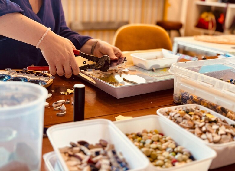 A person working with mosaic tiles on a table. 2