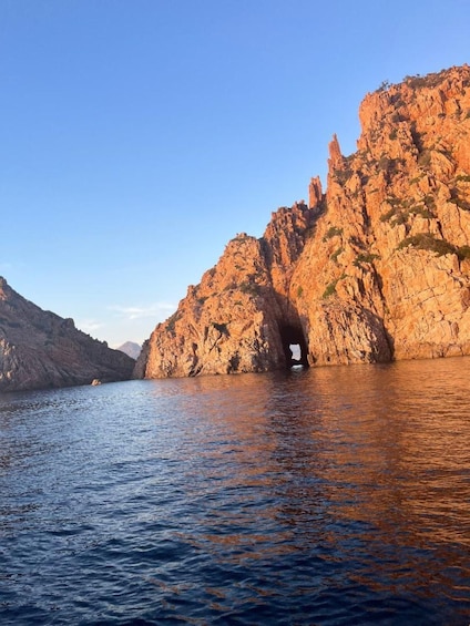 A rocky coastline with a cave entrance and calm waters. 3