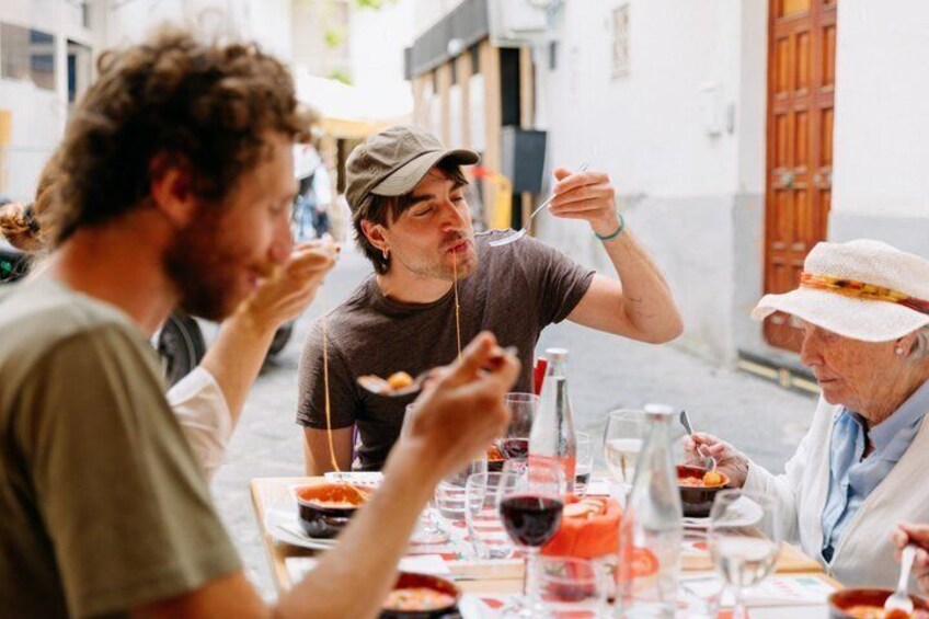A group of people dining outdoors at a table with food and drinks. 1