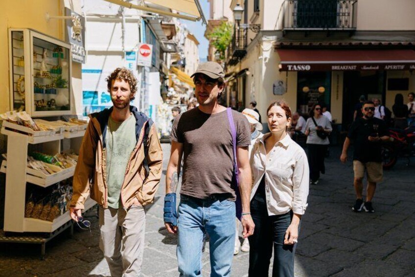 A street scene with people walking, a market stall, and a Tasso restaurant. 5