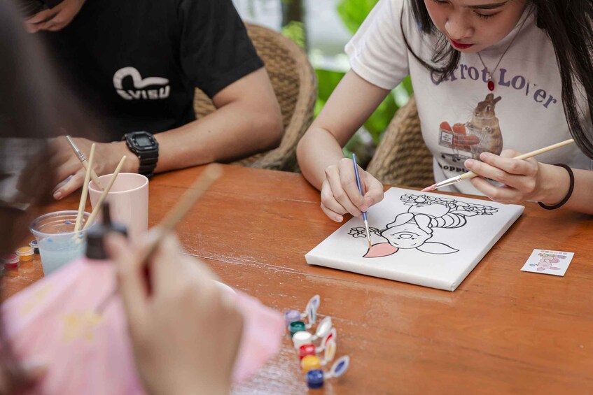 People painting on a canvas at a table. 2