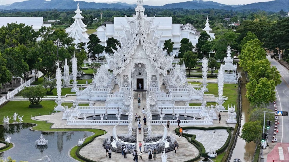 A white ornate temple complex with a central entrance, surrounded by water features and greenery. 2