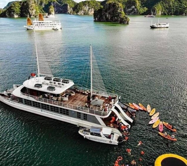 A large boat with a deck area and several kayaks docked at the bow. 2