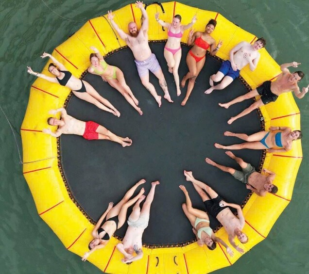 A group of people lying on a circular yellow inflatable raft in a pool. 1