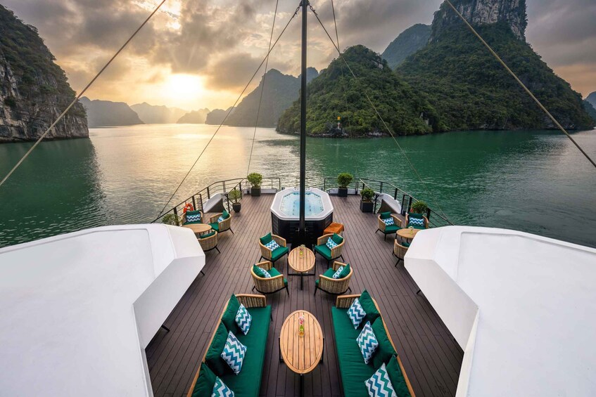 A boat deck with outdoor seating and a hot tub, surrounded by water and mountainous landscape. 3