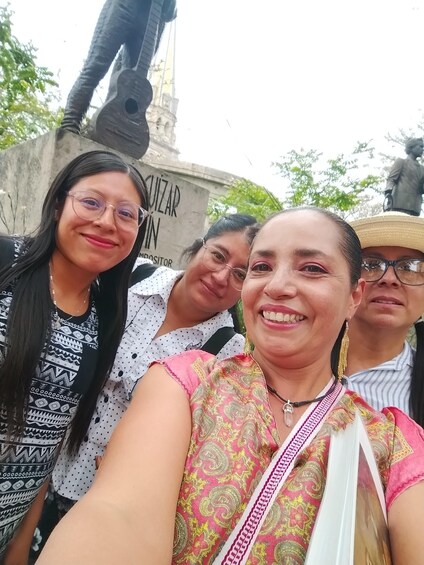 A group of people posing in front of a monument with a statue and a sign that reads 'CUZAR WIN'. 3