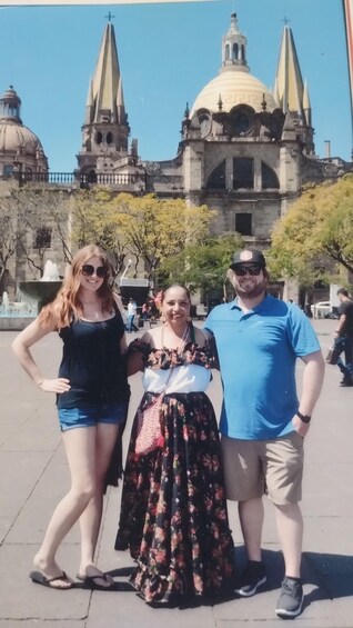 Three people standing in front of a historic building with domes and spires. 5
