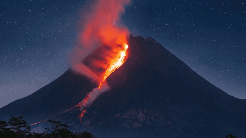 Un volcán en erupción de noche, con lava descendiendo por su ladera. 4