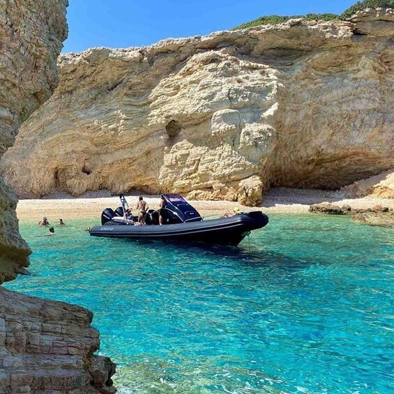 A boat on clear turquoise water with rocky cliffs in the background. 1