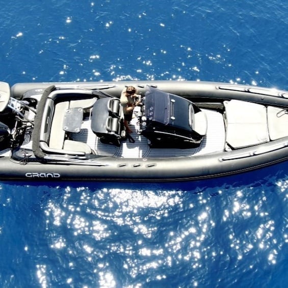 A boat named 'GRAND' on calm blue water with sunlight reflecting off the surface. 2