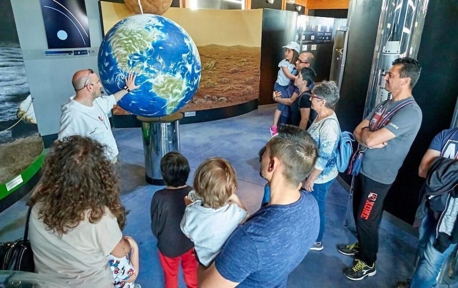 A group of people observing a large globe in an indoor exhibit. 4