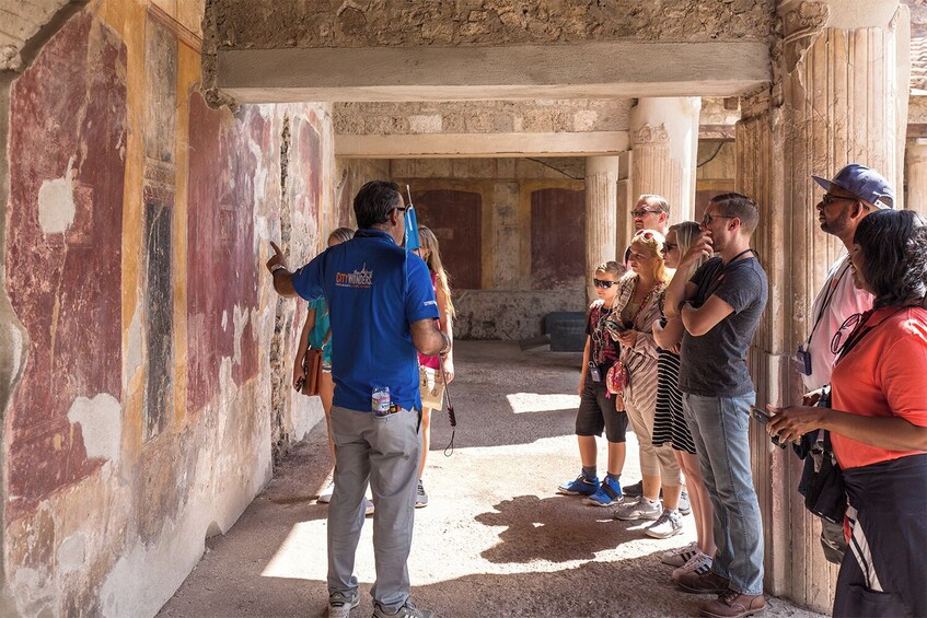 En gruppe turister i en gammel ruin med søjler og forvitrede mure. 1