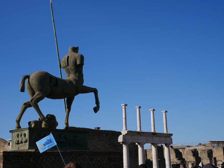 En bronzestatue af en rytter på en piedestal, med søjler i baggrunden. 2